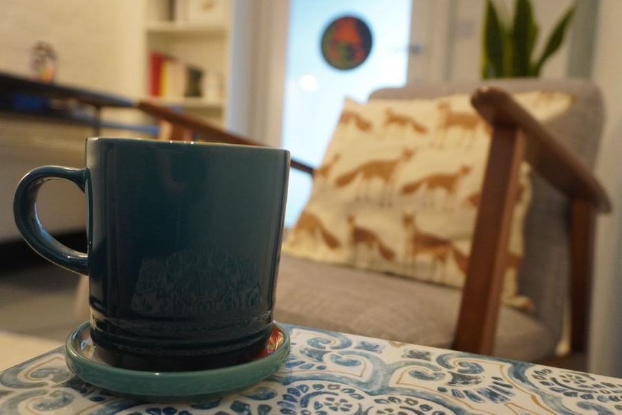 A mug of tea beside the fox cushion in the waiting area